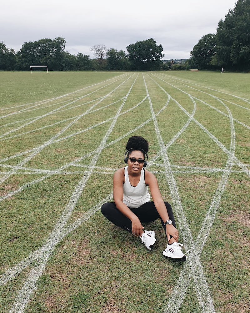 Elle sat on a grass running track holding her ankles - Ankle Strengthening For Runners