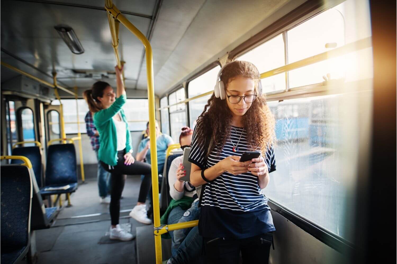 Female student listening to music on headphones on bus, student discounts